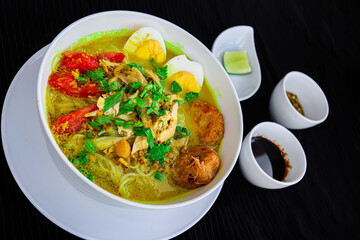 INDONESIAN CULINARY CHICKEN SOUP NOODLE WITH SLICE BOILING EGG AND FRIED MASHED POTATOS AS TOPPING