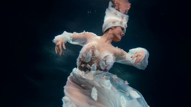 fabulous underwater shot with dancing flower fairy, enigmatic woman in white gown is floating