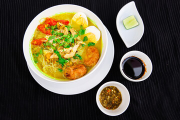 INDONESIAN CULINARY CHICKEN SOUP NOODLE WITH SLICE BOILING EGG AND FRIED MASHED POTATOS AS TOPPING