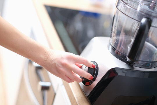 Woman hand presses start of food processor closeup