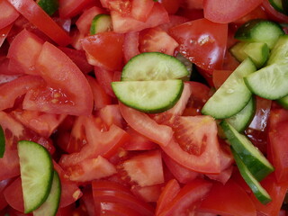 Large red delicious tomatoes and fresh cucumbers sliced for salad. Vitamin food for vegetarians, ready to eat. Ripe fragrant vegetables without spices.