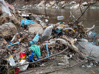 CLOSE UP: Flooded plastic rubbish and other trashes pilled up at the river bank