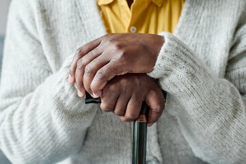 Close-up of African senior man in grey wool jumper leaning on his stick