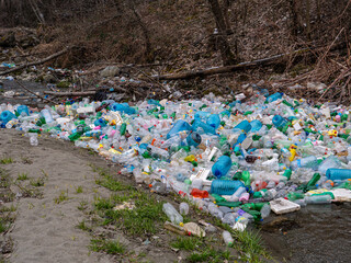 CLOSE UP: Enormous pile of various plastic bottles floating trapped in a branch