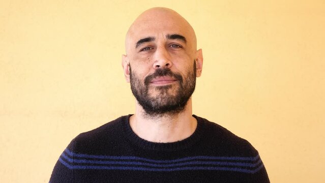 Young handsome looking, bald man with beard posing to camera. 