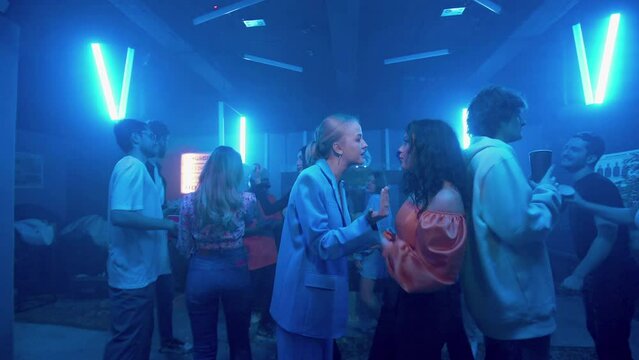 Lesbian girls quarrel among the crowd in a nightclub under the light of colored spotlights. Night club. LGBT