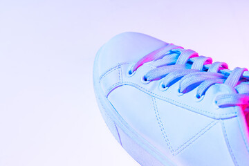 Closeup female sports shoes, sneakers isolated over neoned background. Urban city fashion, fitness, sport, training concept.