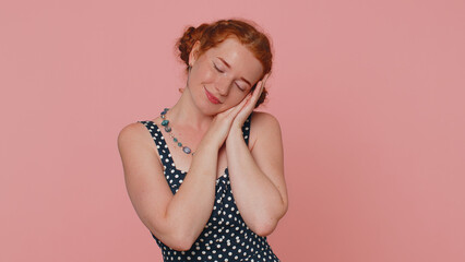 Tired young redhead woman in dress yawning, sleepy inattentive feeling somnolent lazy bored gaping suffering from lack of sleep. Ginger girl with freckles isolated alone on pink studio background
