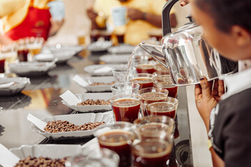 Cropped photo of female employee pouring water from kettle for coffee tasting in production