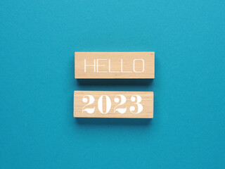 Wooden blocks with the words hello 2023 on a blue paper background, New Year concept