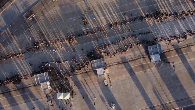 Rotating top down aerial view of long queue during sunset