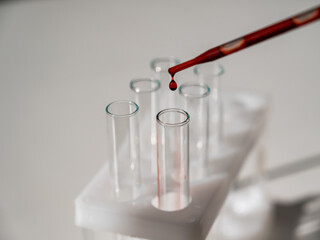 Close-up of a laboratory assistant dripping blood from a pipette into a test tube. 