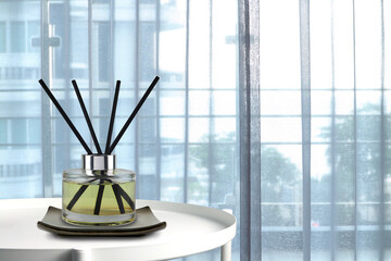luxury aromatic scent of reed diffuser glass bottle is used as room freshener on the steel table in the bedroom to creat relax ambient with background of light from window and curtain in morning