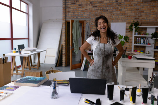 Image of happy biracial female artist looking at camera in studio