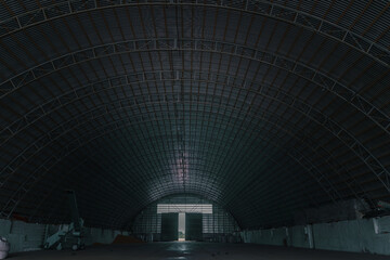 Empty hangar. Manufacturing plant or large warehouse. Metal slabs. Building structure. Dark Background