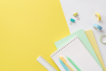 Back to school concept. Top view photo of colorful school accessories notebooks pens ruler adhesive tape and binder clips on bicolor yellow and white background with empty space