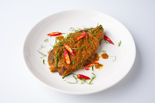 Close up view of Spicy Red Curry with crispy fried fish,  on white dish