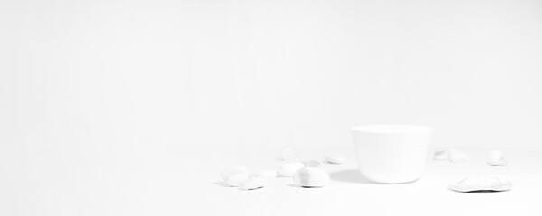 Mockup of a white jar of cream on a white and gray background, on a white table with mineral salt stones, with hard shadows. Stylish product appearance, personality. Banner