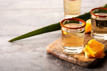 Mezcal Mexican drink with orange slices and worm salt on wooden table. Copy space