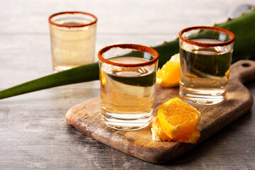 Mezcal Mexican drink with orange slices and worm salt on wooden table	