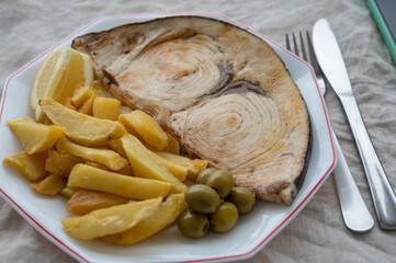 Seafood dish, grilled steak from swordfish or spada served with french fried potatoes and green olives