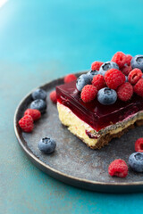 A piece of cake with poppy seeds and berry jelly, cake on a plate decorated with juicy raspberries and blueberries