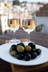 Glass bowl with black andalusian olives served with sherry wine on outdoor terrace with view on old part of Granada, Andalusia, Spain