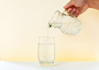 Pouring water from glass pitcher to glass.