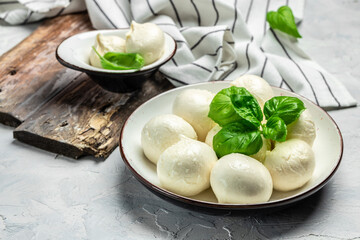 Cheese collection, white balls of soft Italian cheese mozzarella, served with fresh basil leaves on...