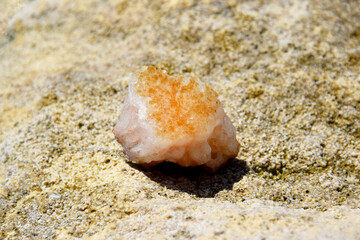 A beautiful druse citrine lies on a stone. Intergrowth of yellow crystals of semi-precious quartz in bright sunlight.