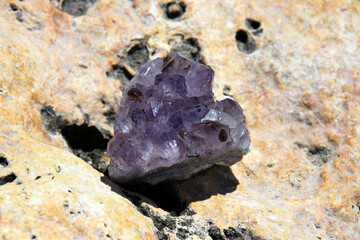 Beautiful purple amethyst crystals on a yellow stone by the sea. Bright purple amethyst druze in the shape of a heart against the background of the sea.