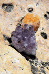 Beautiful purple crystals of amethyst and druse cetrinum on a yellow stone on the seashore. Bright...