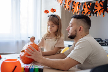 father and daughter making Halloween home decorations together. focus on man.