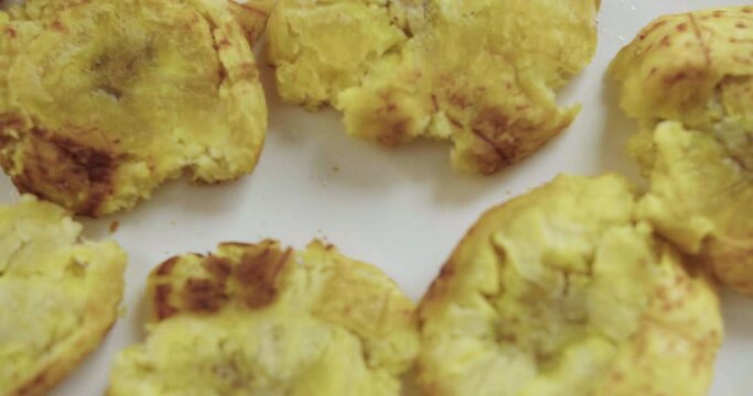 Plano detalle de patacones o tostones reci&eacute;n cocinados y crocantes sobre un plato blanco.