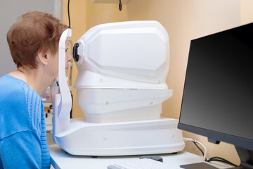 An adult woman at an ophthalmologist's appointment checks her vision on a special apparatus....