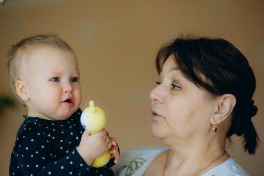 little caucasian baby girl and grandmother. woman hugging granddaugher with love