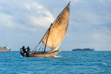 sailing dhow heading for harbour full sails and choppy ocean