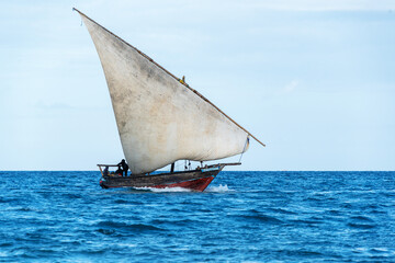 sailing dhow heading for harbour full sails and choppy ocean - obrazy, fototapety, plakaty
