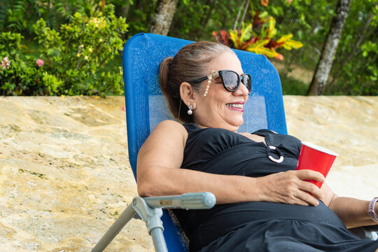 Senior Woman Relaxing In Lounge Chair At Pool