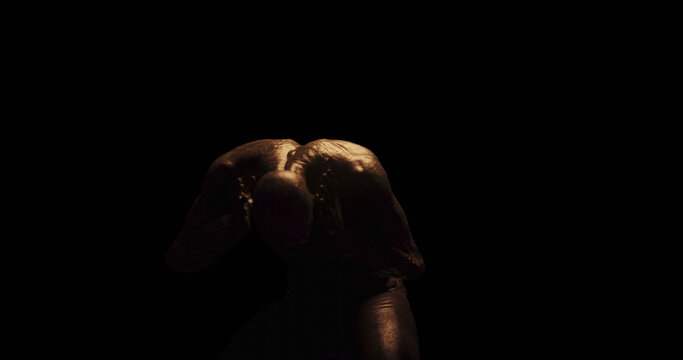 Image of distressed shirtless bald figure holding head in pain in dark room