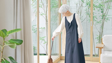 掃除をするシニア女性 © metamorworks