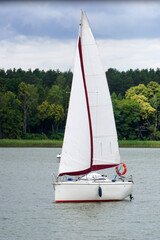 Sailboat swimming on a lake - trees on shore