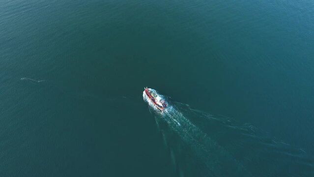 An aerial view from a drone flying above a fishing boat moving forward on the sea. dynamic aerial shot. tropical sea in the Gulf of Chumphon Province, Thailand. Drone 4k shot.
