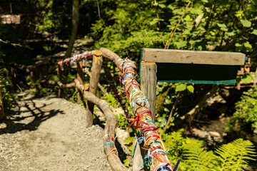 Wooden bridge over a mountain river with tied ribbons fulfilling a wish