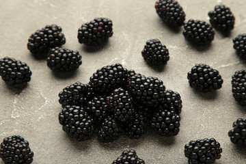 Close-up view on juicy and tasty blackberry fruits laying on grey table. Selective focus. Vitamins in fresh fruits concept.