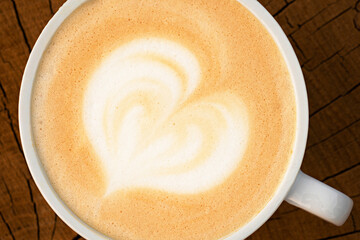 Cup of cappuccino with a heart on a wooden surface. Close up