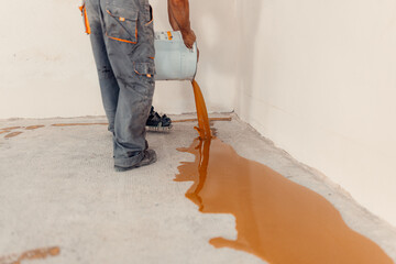 Worker applying a yellow epoxy resin bucket on floor.