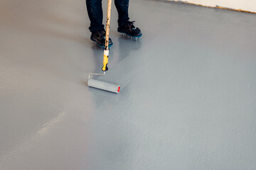 Construction worker apply grey epoxy resin in an industrial hall