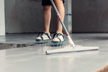 A construction worker apply grey epoxy resin in an industrial hall