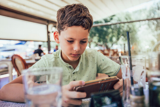 Boy addicted online games outdoors. Boy use phone and plays games.